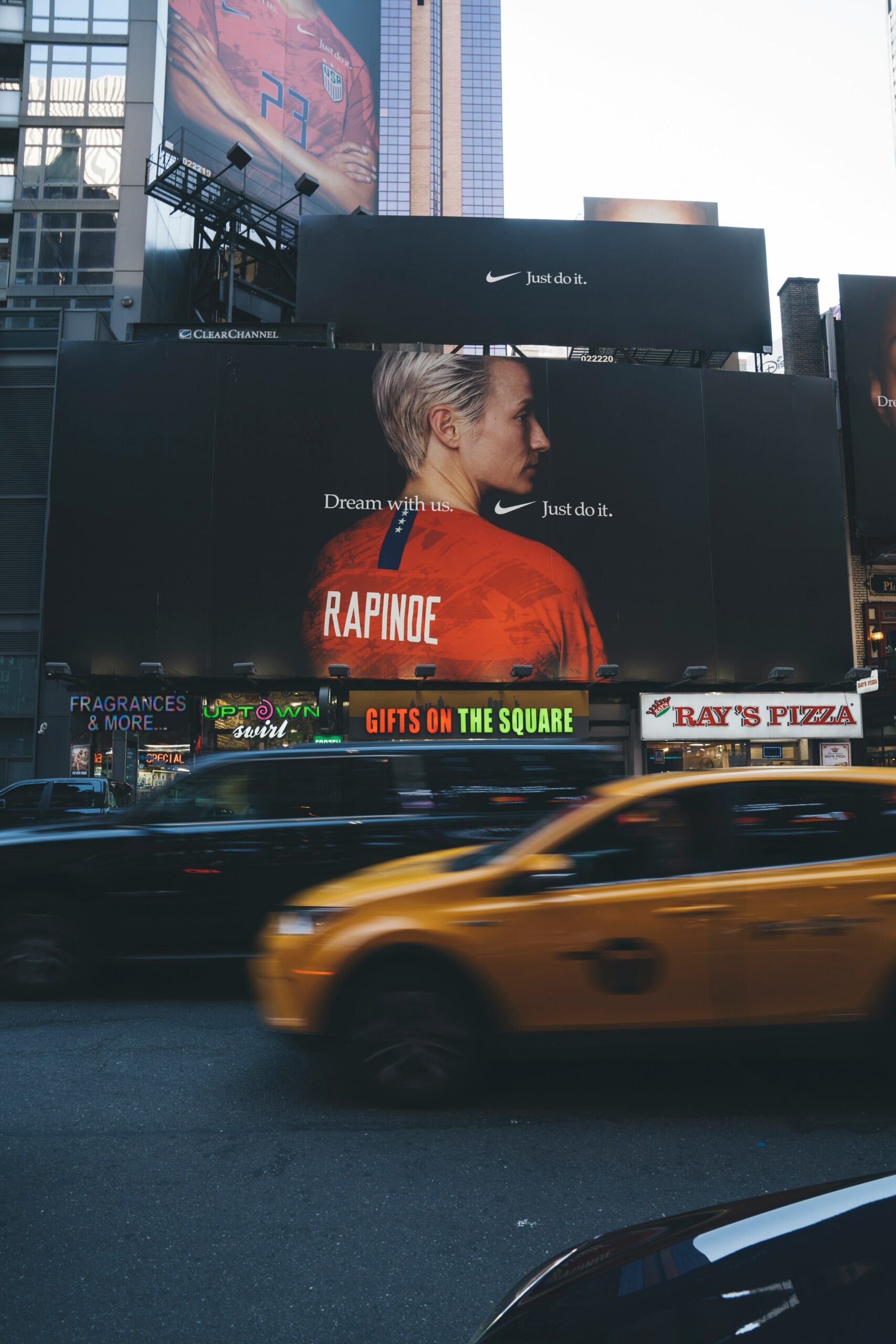 a nike billboard in a city with a cab driving by