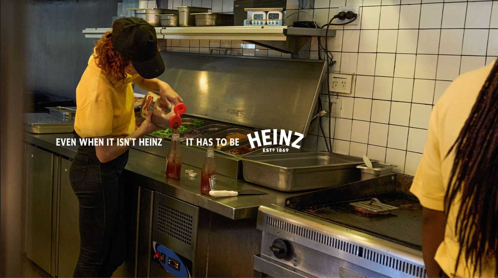 girl in kitchen pouring ketchup in a heinz bottle
