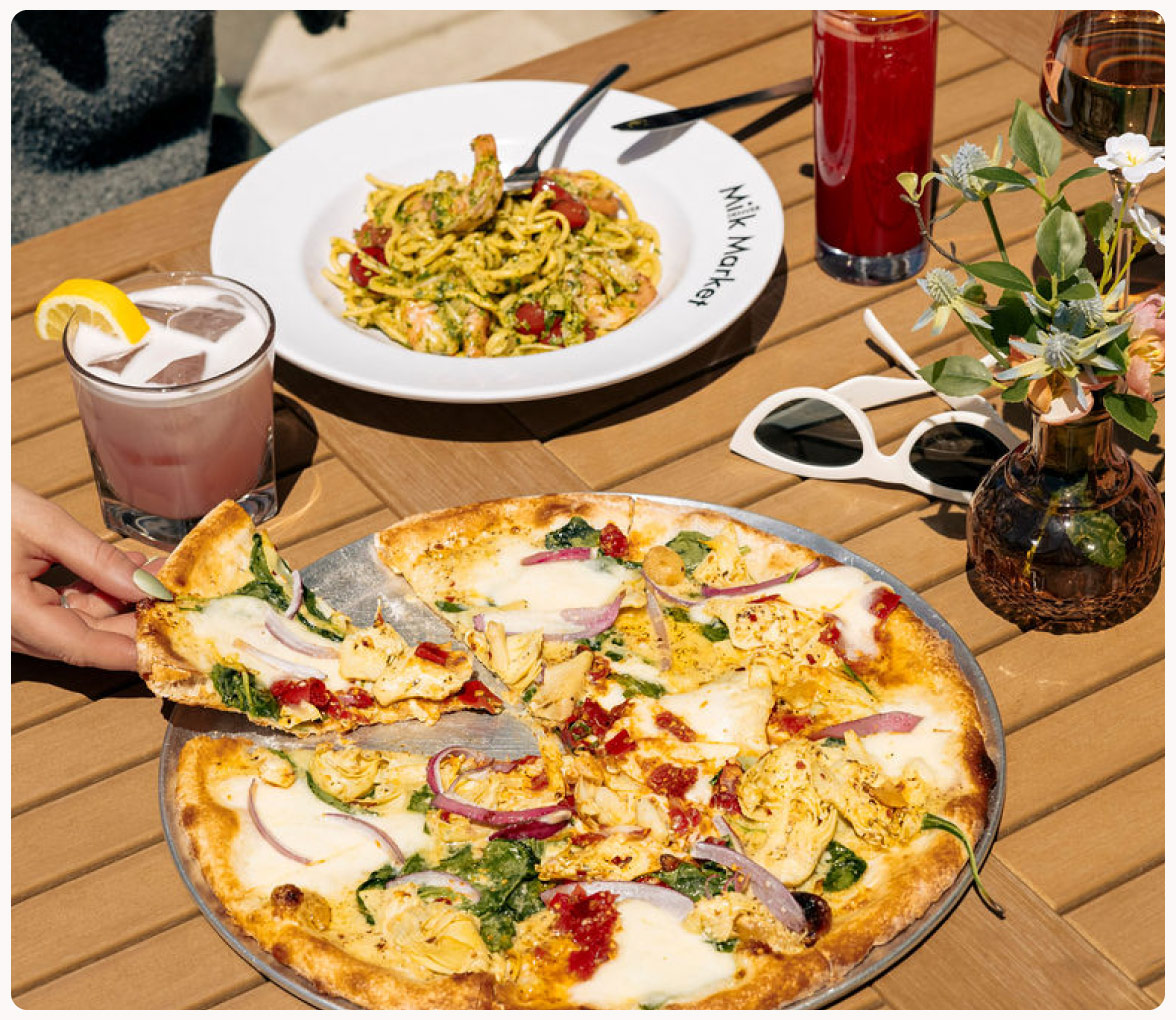 Sunny outdoor dining featuring pizza, pasta, and a cocktails