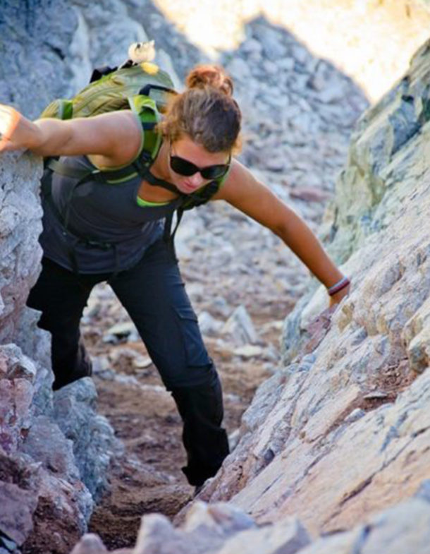 Woman climbing on rocks while hiking