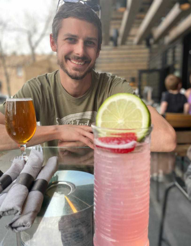 Person smiling at a table with drinks.