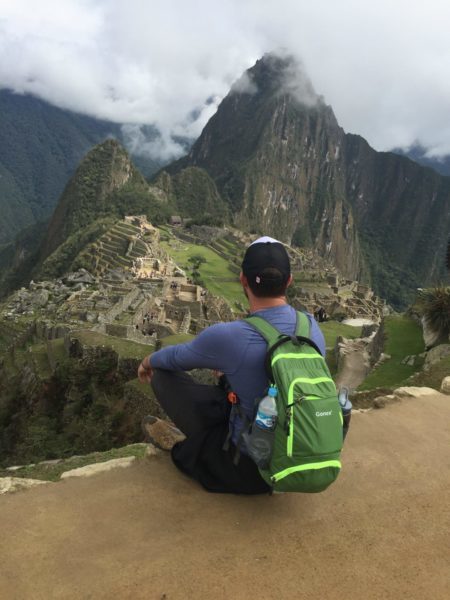 Person with backpack at Machu Picchu viewpoint.