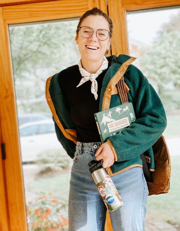 Person smiling, holding book titled 